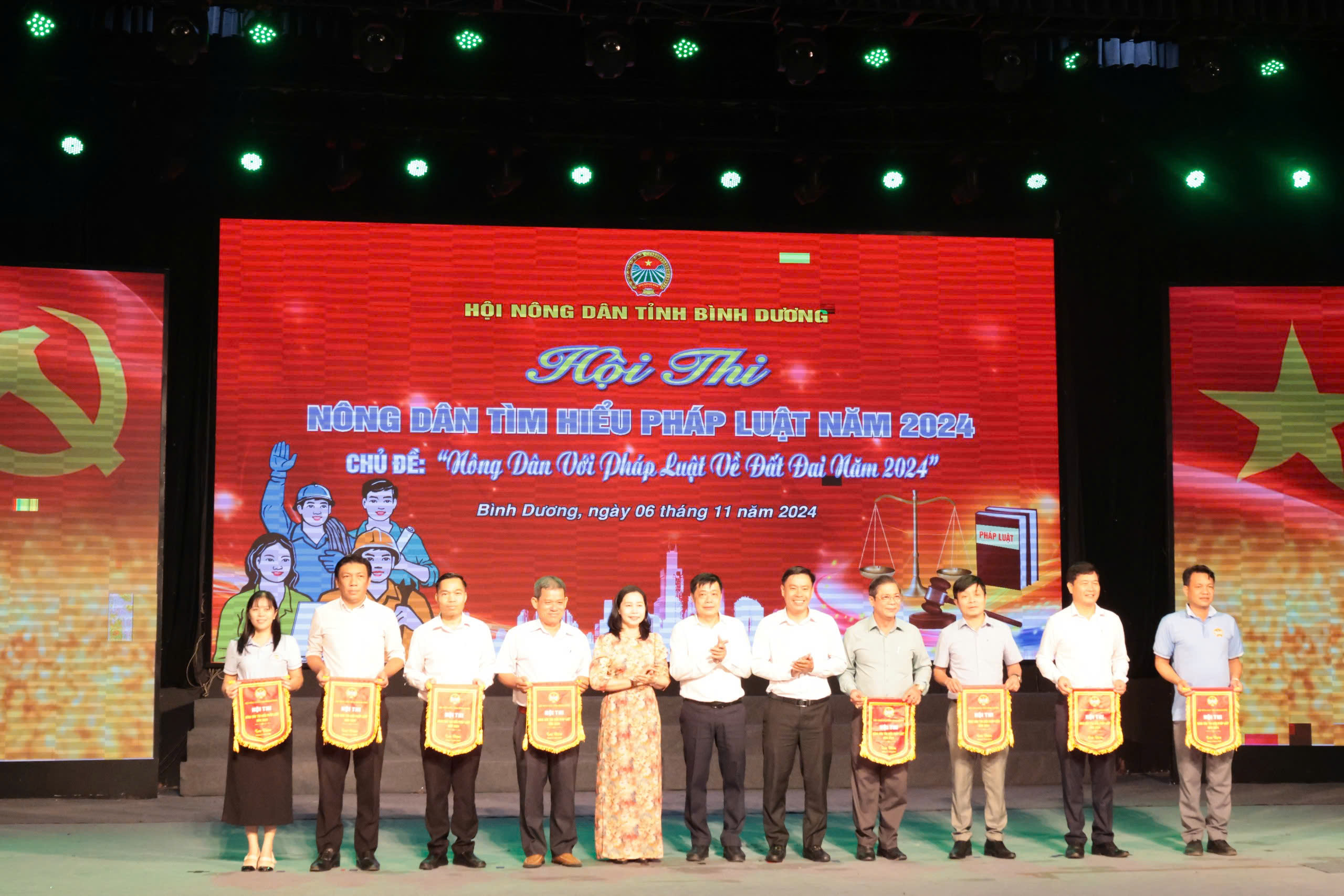 A group of people standing on a stage holding signsDescription automatically generated